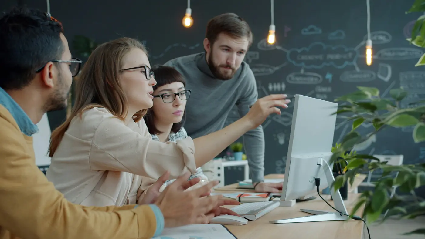 A team discussing a project together around a computer screen
