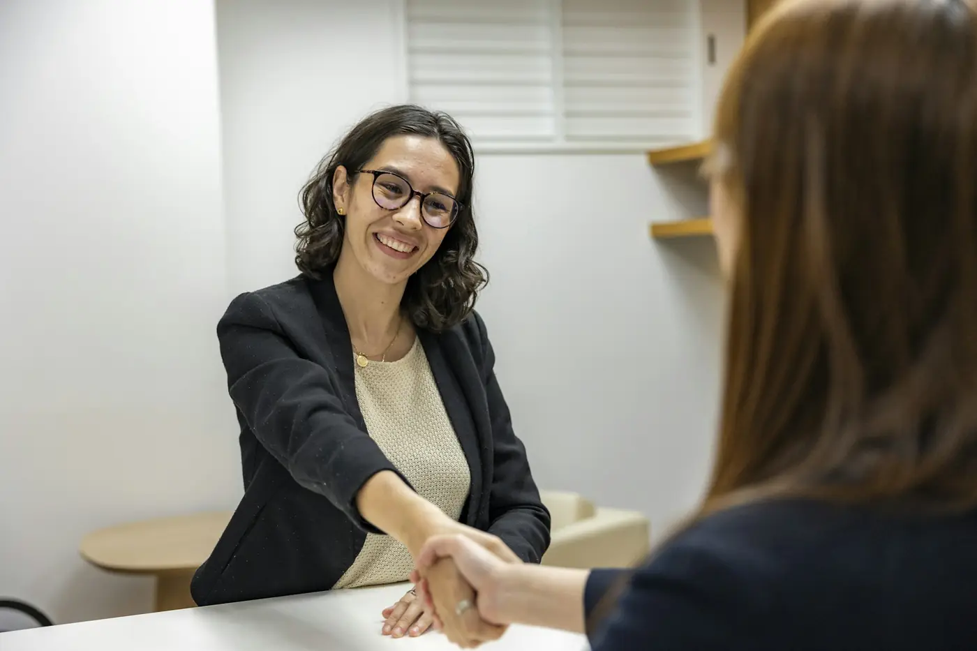 A recruiter smiling and shaking hands with a candidate